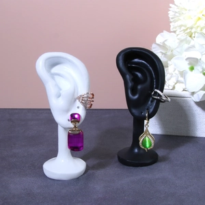 Realistic ear model display stands with assorted colorful gemstone earrings and ear cuffs