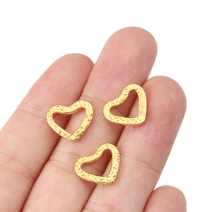Three gold textured hollow heart charms for jewelry making shown on a fingertip
