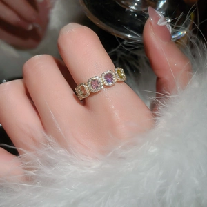 Macro detail of 14k gold plated ring with colorful zircon stones on a feather background