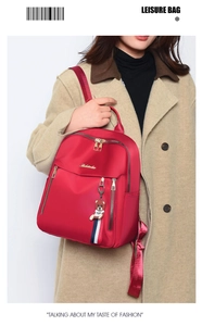 Red nylon backpack for women styled with a casual coat and a cute bear accessory
