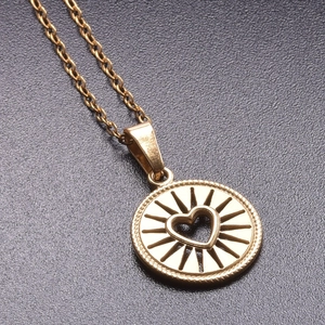 Macro shot of gold-plated circular sunburst pendant with a hollow heart detail