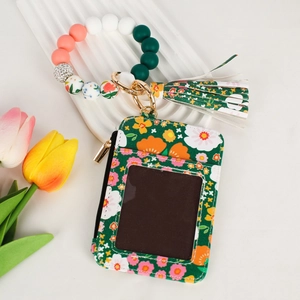 Detail of floral zipper card wallet with silicone beaded bracelet and tassel keychain