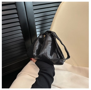 Gros plan d'un sac à main noir à paillettes montrant la texture brillante du tissu à la main