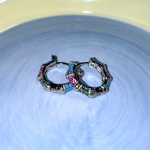 Détail de boucles d'oreilles en argent style bambou avec zircons roses verts et bleus