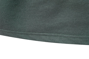 Detailed close-up of dark green mesh fabric texture and double-stitched hem on polo shirt