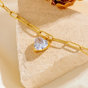 Elegant gold heart pendant necklace with paperclip chain on a textured stone background