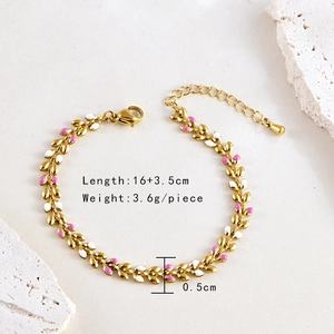 Bohemian gold wheat leaf bracelet with pink and white enamel on a white stone background