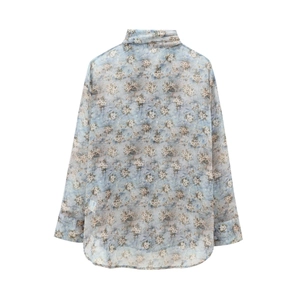 Détail d'une chemise en mousseline bleu clair à fleurs avec manches longues et tissu fin