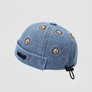 Détail du bonnet docker enfant en denim bleu avec broderie ours et cordon de serrage réglable