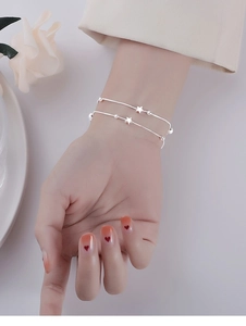Close-up of a double-layered silver star bracelet on a wrist with minimalist design