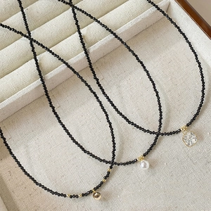 Vue détaillée de colliers en perles noires avec pendentifs en perle et en cristal