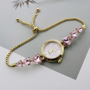 Detail of gold quartz watch with pink heart gemstones and mother of pearl dial