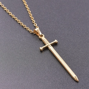Macro detail of golden sword pendant with intricate cross guard and spiral hilt texture