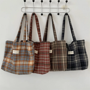 Detail of four colorful plaid wool tote bags hanging showing texture and canvas labels