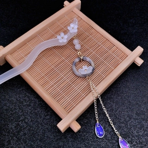 Close-up of white flower hair stick with golden tassels on a bamboo tea tray