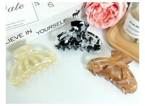 Detailed set of three tortoise and marble acetate hair claws on a decorative tray