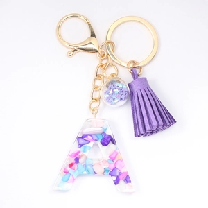 Detailed view of resin letter A keychain with colorful stones, purple tassel and gold hardware