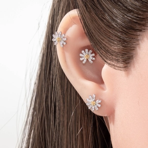 Silver daisy stud earrings with yellow center and zircon micro-paving on model's ear