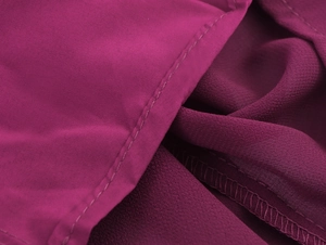 Détail du tissu en mousseline magenta montrant la couture et la texture plissée