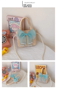 Detail view of off-white straw woven kids bag with blue mesh bow and white pearls