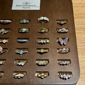 Chic gold-plated enamel butterfly and floral rings set on a wooden display stand