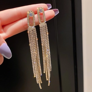 Détail des boucles d'oreilles à franges dorées avec zircone cubique taille émeraude