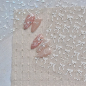 Macro detail of 3D embossed white butterfly and bow nail art stickers on beige linen fabric
