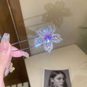 Macro shot of silver flower hair pin with iridescent crystals and floral shadow on wall
