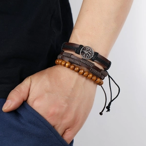 Close-up of vintage leather bracelet set with tree of life charm and wooden beads on wrist