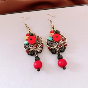 Detailed view of vintage dragonfly earrings with red floral beads and gold-tone accents