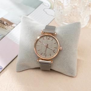 Detail of rose gold quartz watch with grey leaf-pattern dial on grey velvet cushion