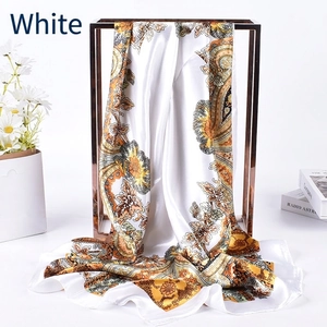 Close-up of white silk scarf featuring orange paisley prints and floral patterns