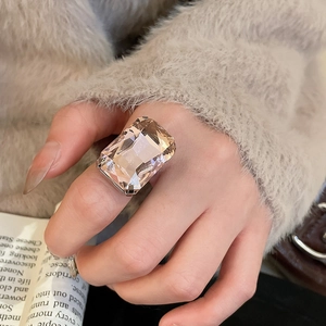 Macro shot of rectangular champagne crystal ring with claw setting worn on index finger