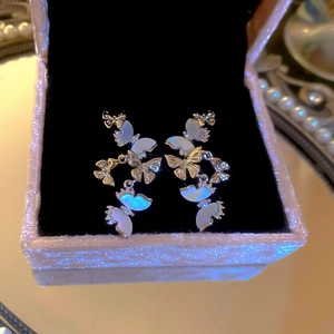 Detail view of silver butterfly tassel earrings with zircon and mother of pearl on velvet
