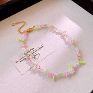 Detailed macro view of handmade floral ceramic bead necklace with gold lobster clasp