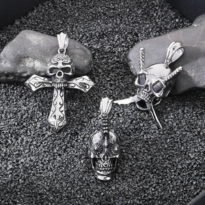 Macro shot of silver stainless steel gothic skull and cross pendants on dark stones