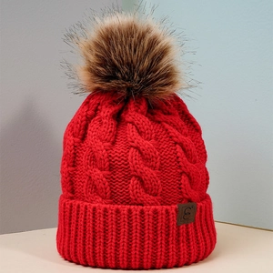 Red cable knit beanie with faux fur pompom and leather logo patch for winter warmth
