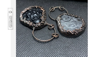 Detail von handgeschnitzten Buddha-Anhängern aus Kristall und Obsidian mit Bronzerand