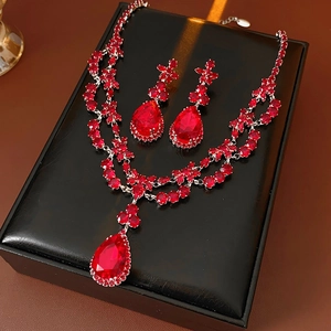 Detail of red zircon flower teardrop necklace and earrings set on black leather box