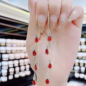 Elegant gold-tone tassel earrings featuring red teardrop gems and sparkling rhinestones