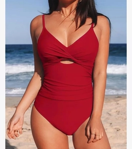 Detail of red one-piece swimsuit featuring textured ruched fabric and knot cutout design