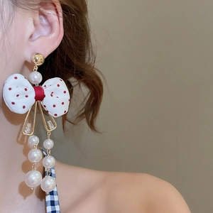 Detailed close-up of sweet bow earrings featuring red polka dots and dangling white pearls