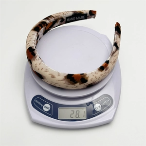 Detail showing the 28.1g weight of the leopard print plush headband on a scale