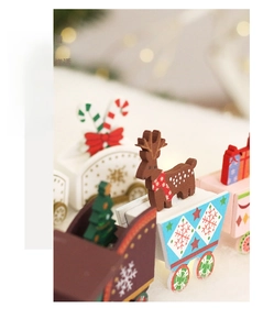 Close-up of painted wooden Christmas train with reindeer and tree on festive bokeh background