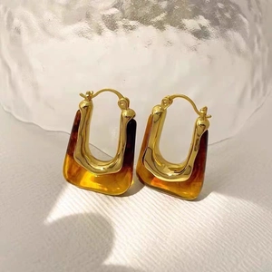 U-shaped 18K gold plated earrings with amber resin detail on textured background