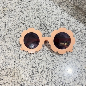Macro shot of pink flower-shaped toddler sunglasses with UV400 protection lens