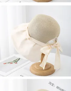 Detail of straw sun hat featuring a large fabric brim and elegant bow decoration