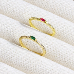 Close-up of gold rings with red and green marquise stones in a jewelry box