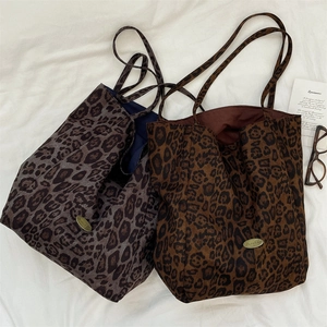 Top view of two leopard print canvas tote bags in grey and brown with golden logo plates