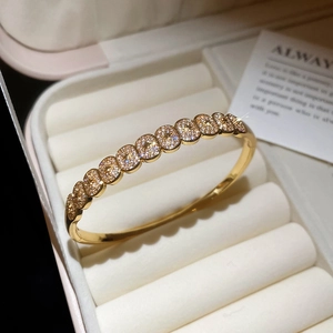 Close-up of gold plated bangle with pavé zircons in a white velvet jewelry box
